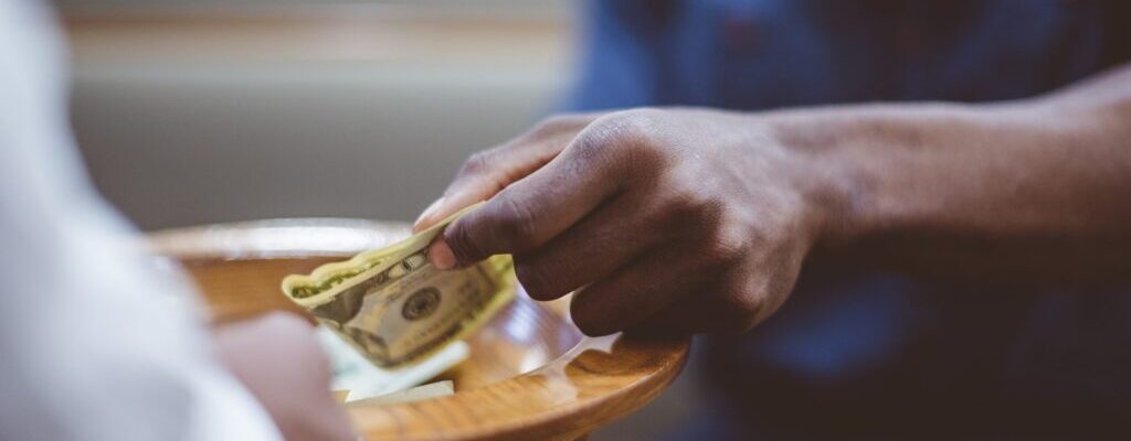 A closeup shot of a male donating money for church with a blurred background